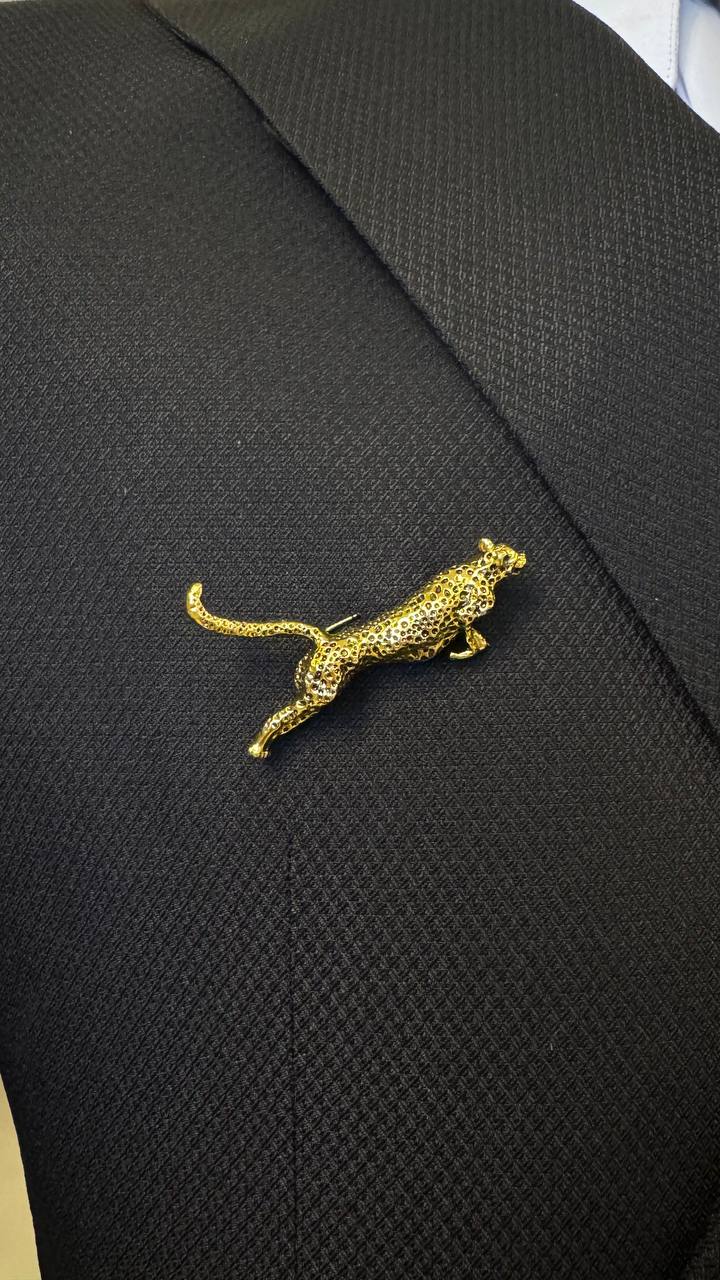Gold leopard brooch detail on black suit fabric