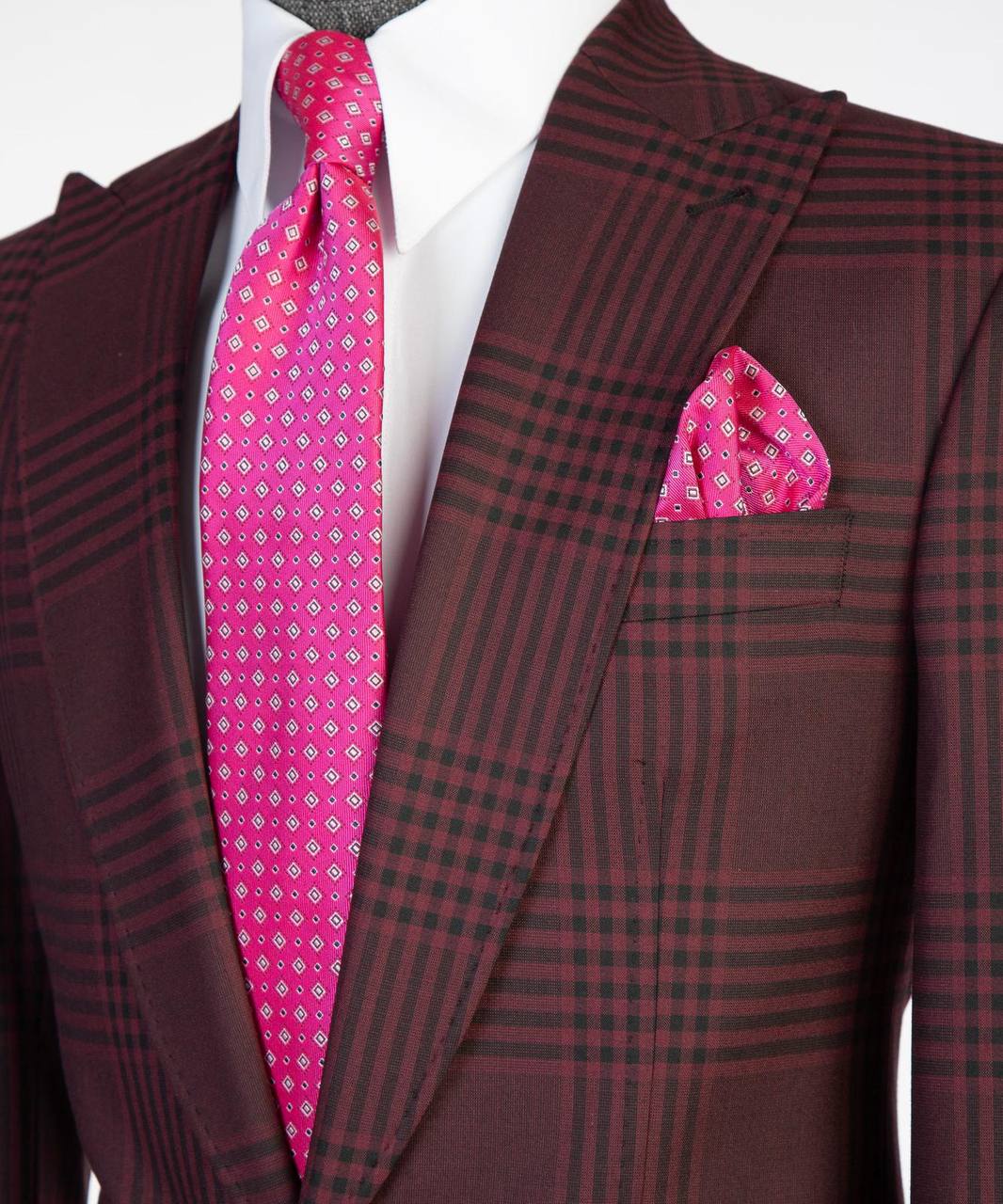 Close-up of burgundy plaid suit jacket styled with white shirt, pink tie, and pocket square.