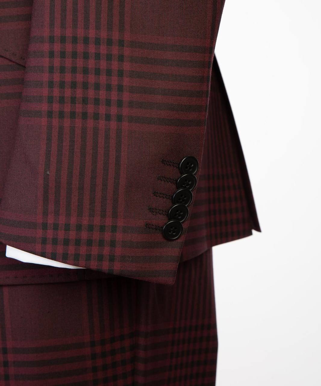 Detail view of burgundy plaid suit sleeve buttons and matching trousers.