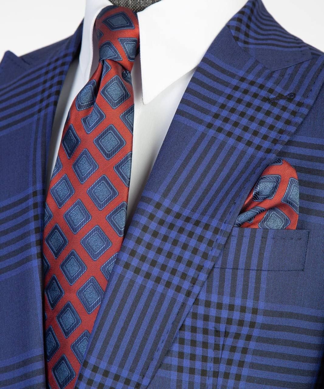 Close-up of blue plaid suit jacket styled with white shirt, red patterned tie, and pocket square.